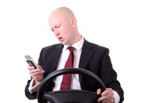 A man is looking at his phone while driving, making a voice query.