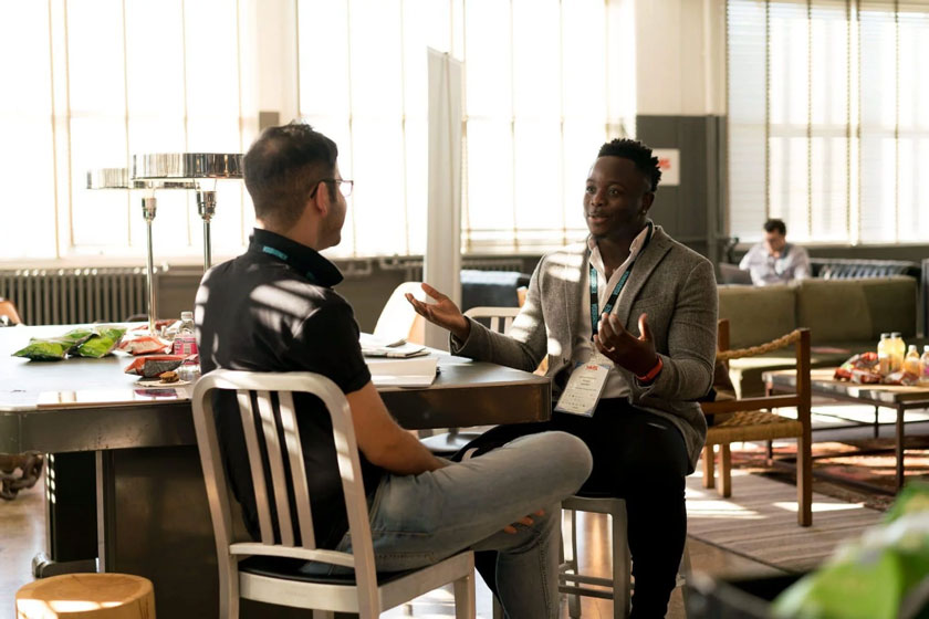 Two people in the middle of a discussion, sitting face to face inside an office cafeteria