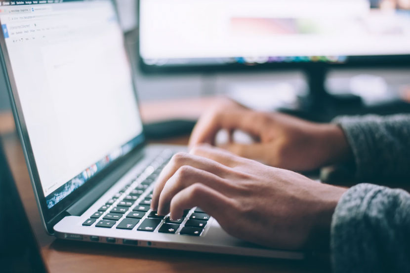 A person typing on a laptop’s keypad