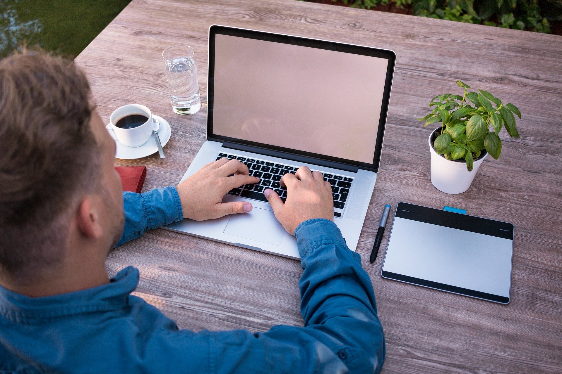 man in blue long sleeves typing on a laptop