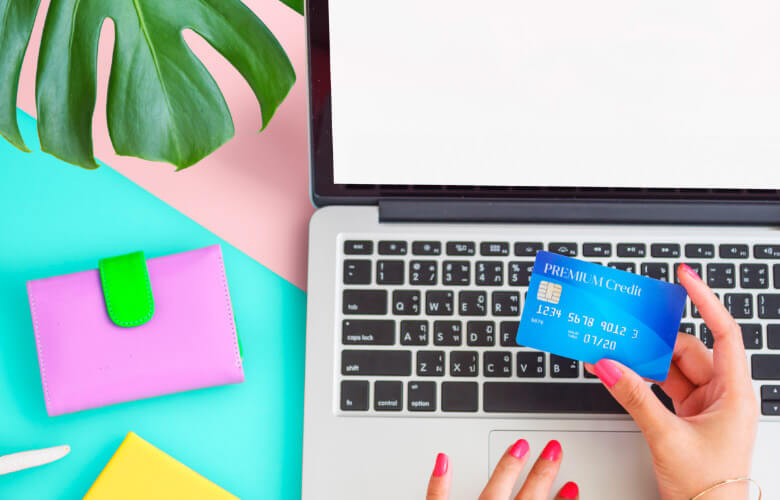 person holding a credit card with laptop on a table