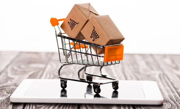 mini shopping cart with boxes on top of a white cellphone