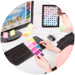 A graphic designer organizing color swatches on a desk with multiple digital displays showcasing designs.